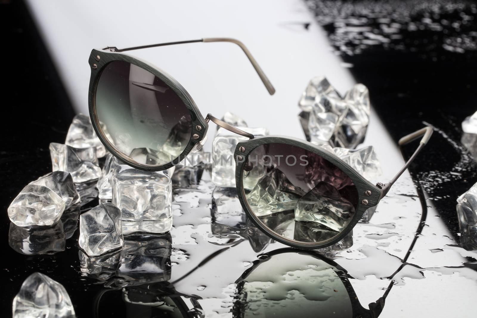Sunglasses and crystals of ice on a studio glass background