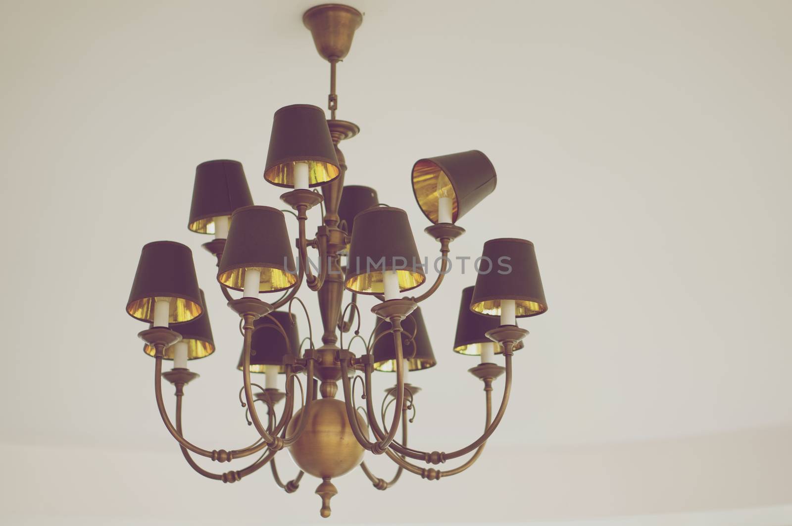 Chandelier made from brass on white ceiling in vintage style.