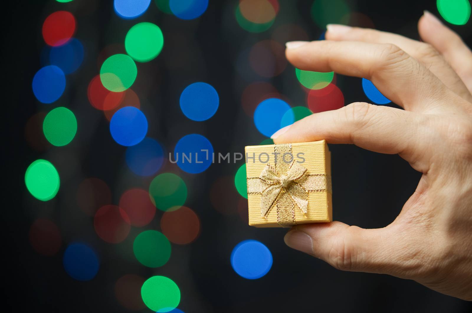 Hand of man pinch present have colorful bokeh as background.