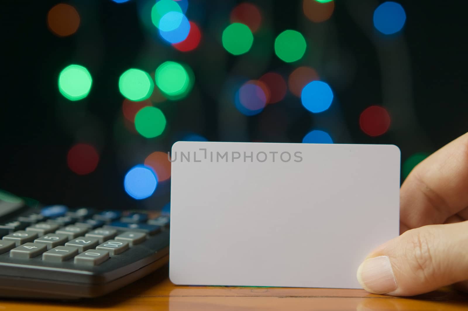 Man pick empty card with calculator on wood table have colorful bokeh as background.