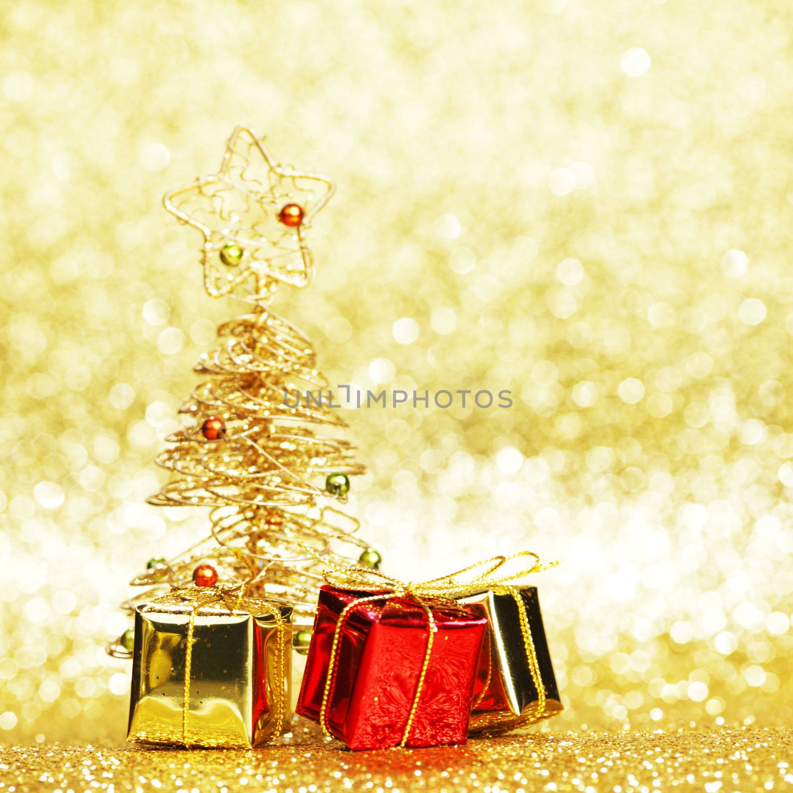Decorative golden toy christmas tree and gifts on golden background