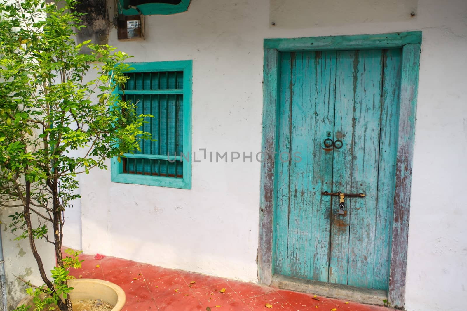 a House in George Town, Penang, Malaysia. Mediterranean style exterior. Blue wooden doors and window shutters on old painted wall