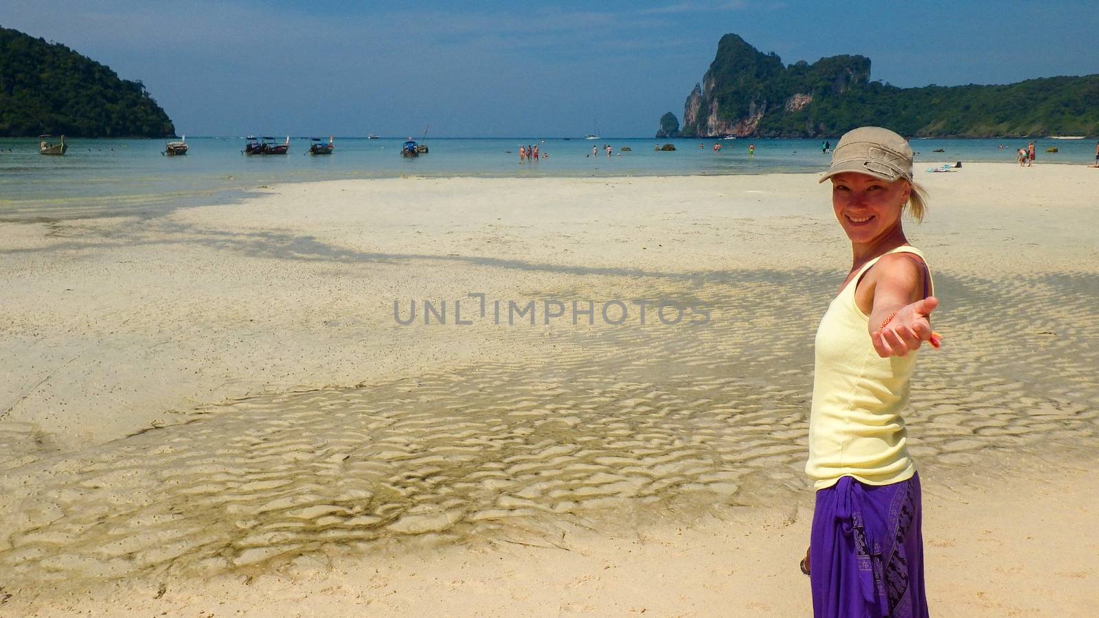 pretty woman waving by hand while standing in the sea and looking at camera