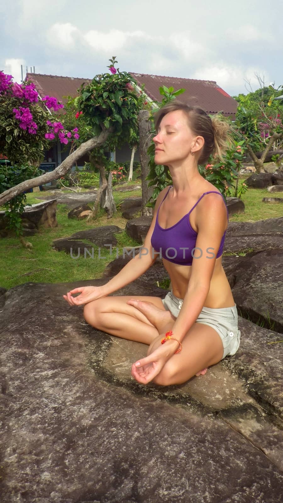 a young woman sitting in yoga lotus pose meditation outdoors