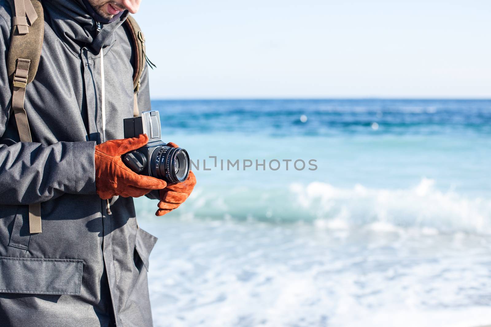 Man hold in hand a vintage old camera on the seashore background