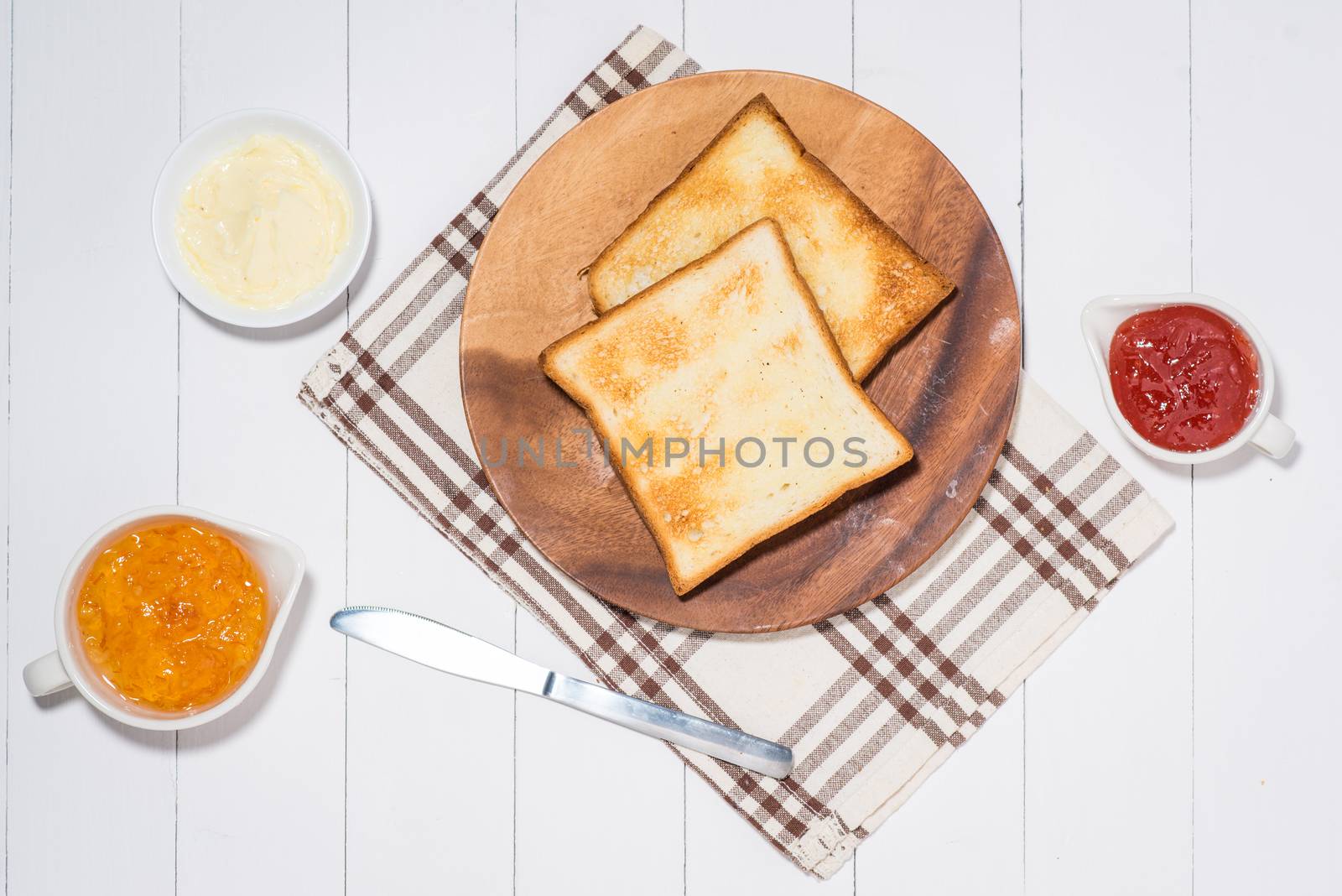 Close-up of slice of toast bread with jam and butter on wood table
