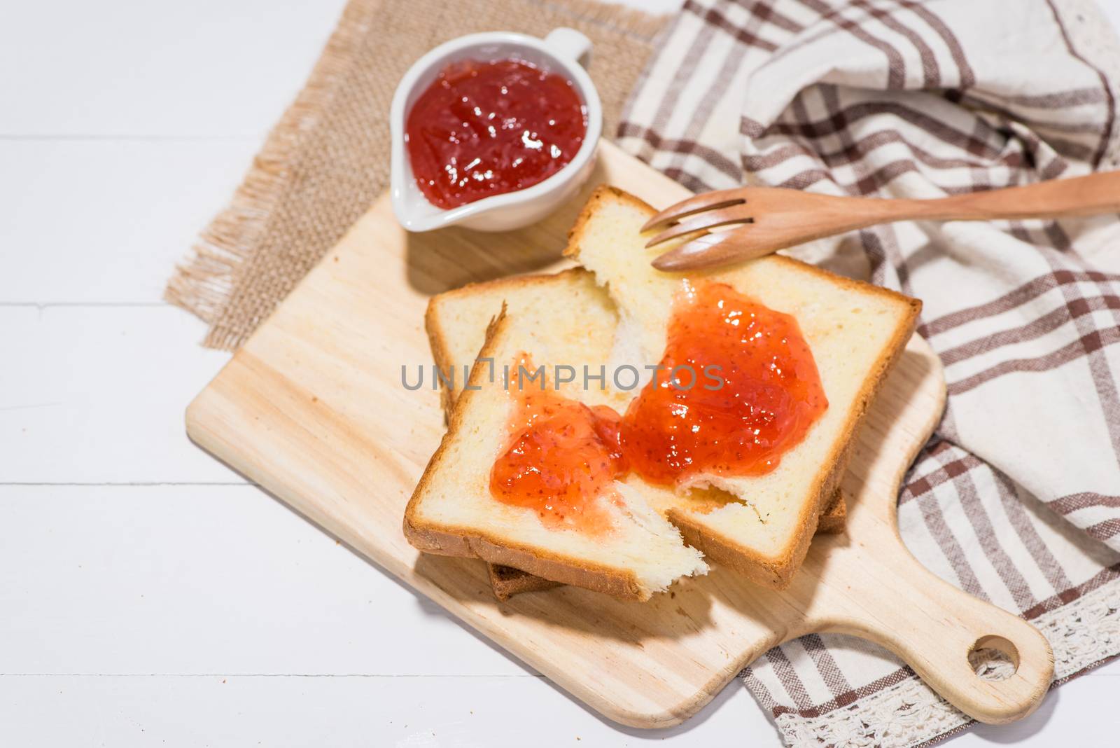 Toast with strawberry jam on a plate on table.