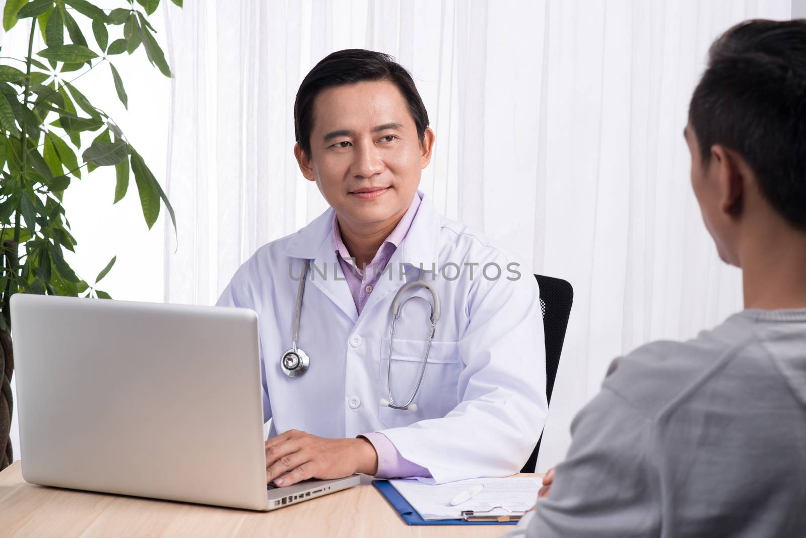 Confident asian male doctor discussing diagnosis with patient in office by makidotvn