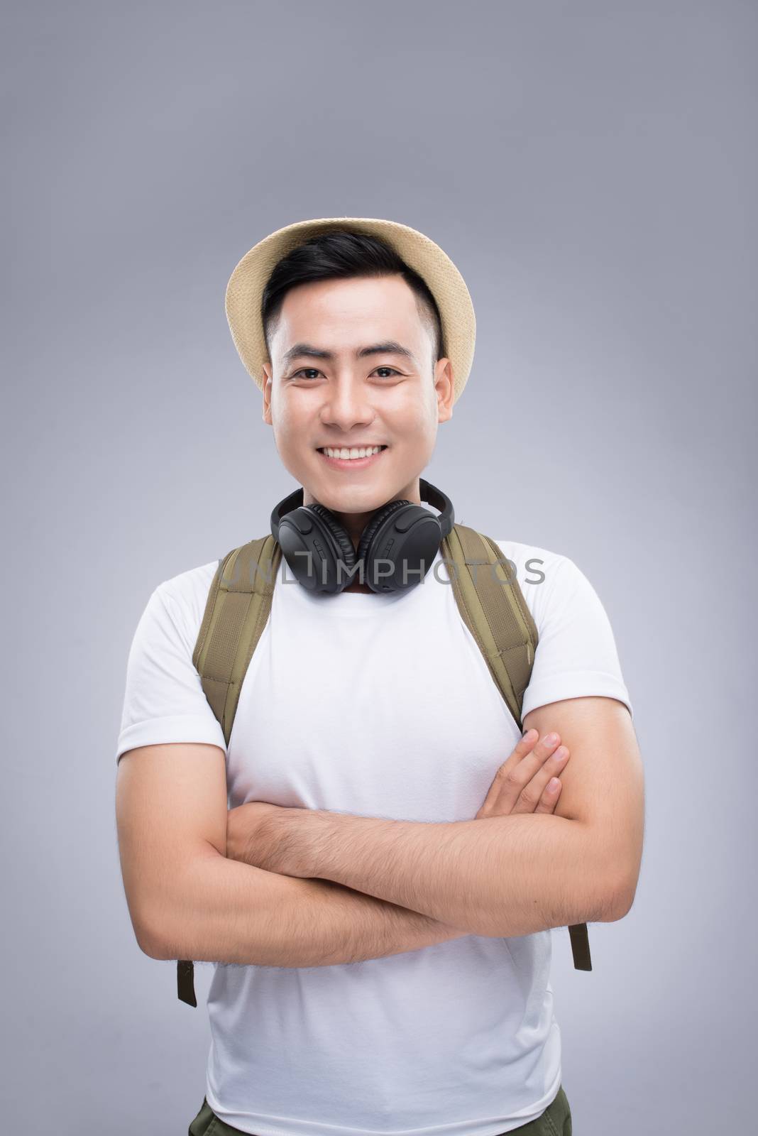 Travel concept. Studio portrait of handsome young man in hat with backpack.