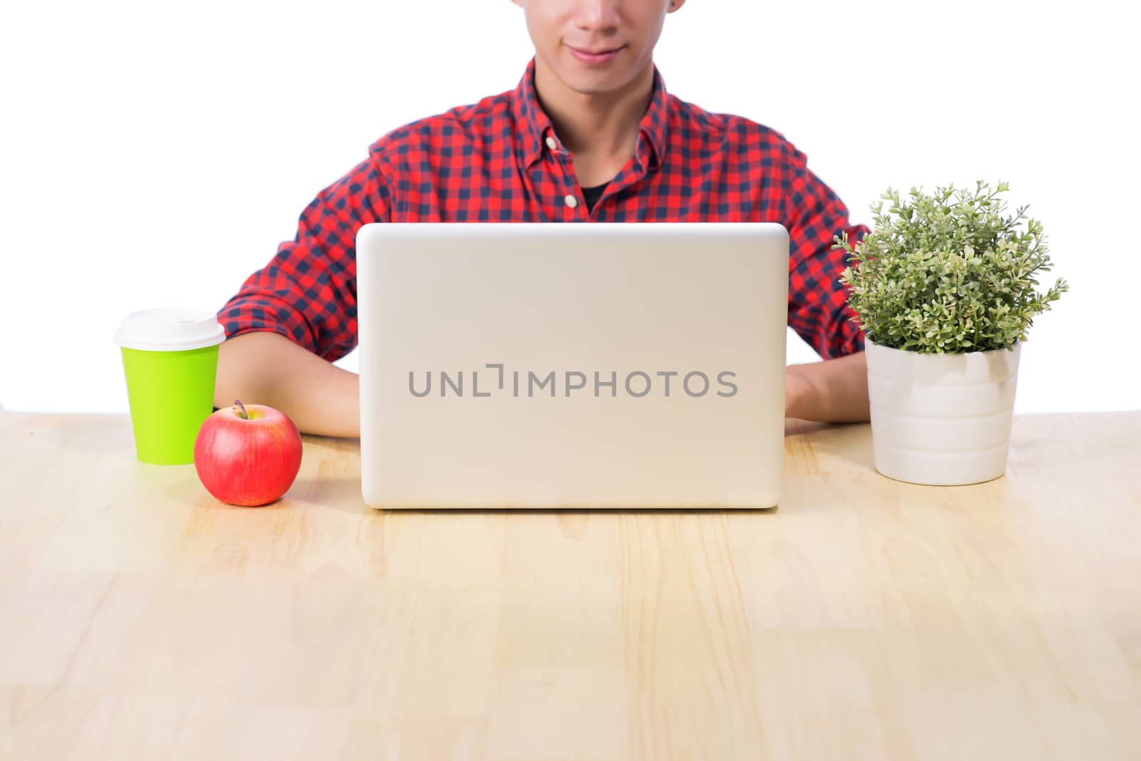 Cropped image of male studio using laptop with red apple at desk.