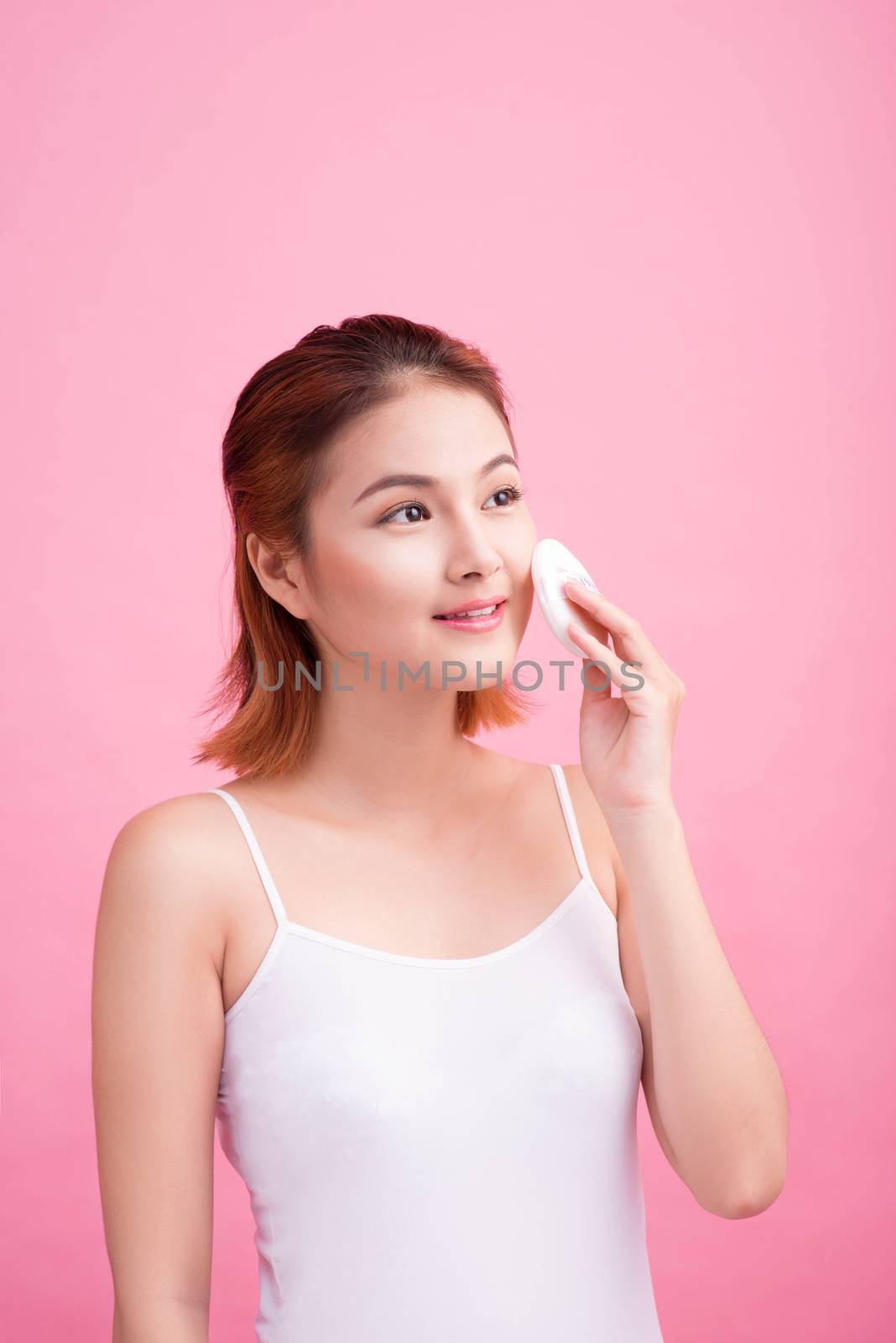 Young lady applying blusher on her face with powder puff, skin c by makidotvn