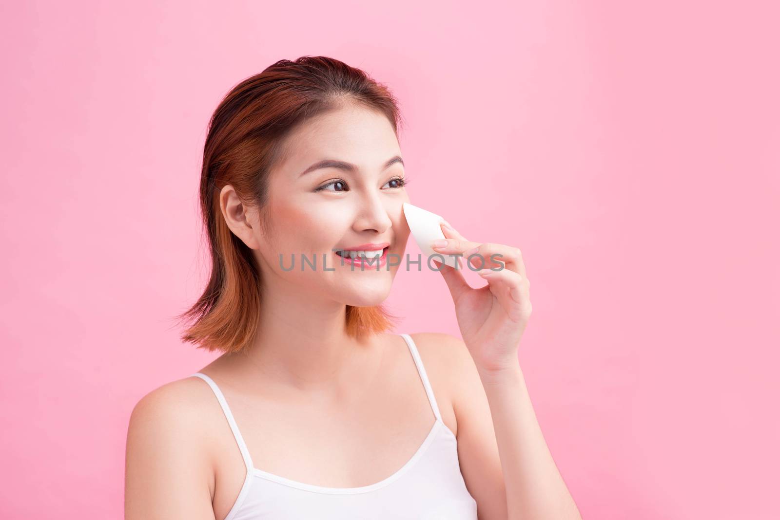 Young lady applying blusher on her face with powder puff, skin c by makidotvn
