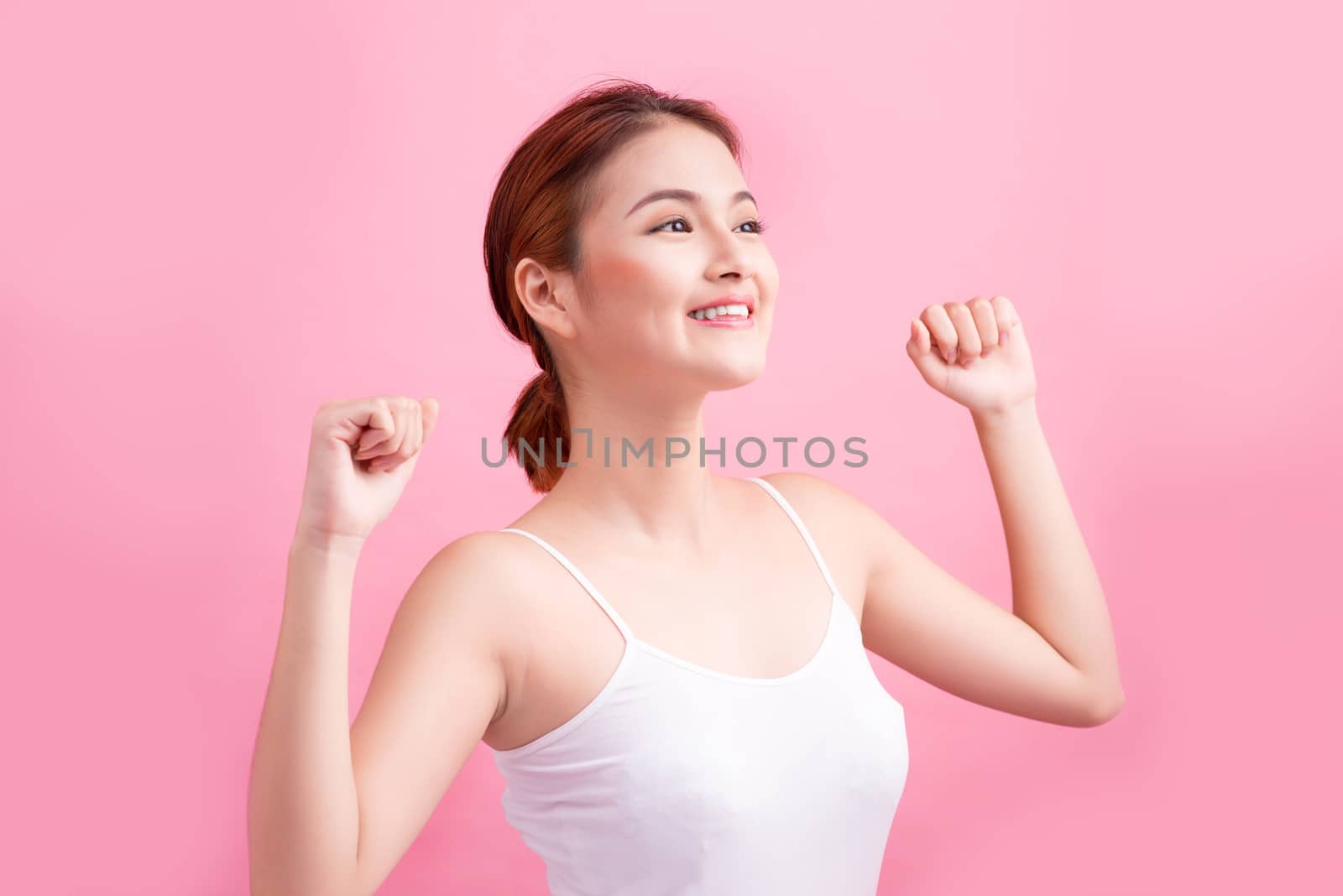 Portrait of a carefree young asian woman smiling with arms raise by makidotvn