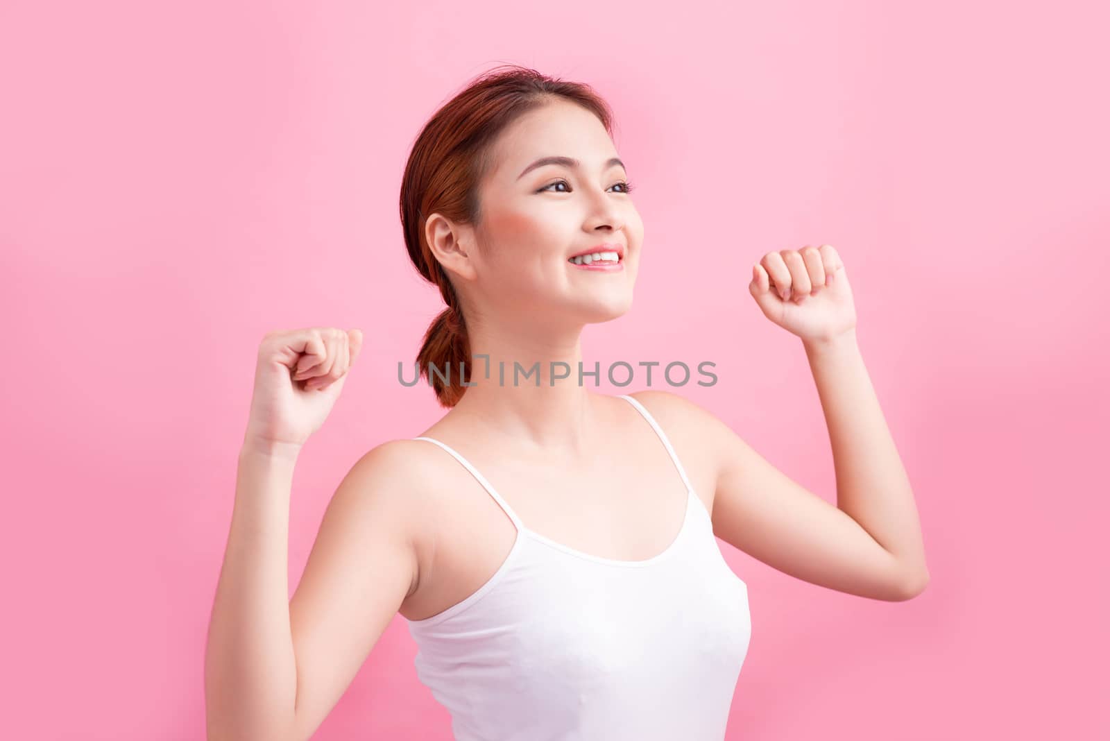 Portrait of a carefree young asian woman smiling with arms raised