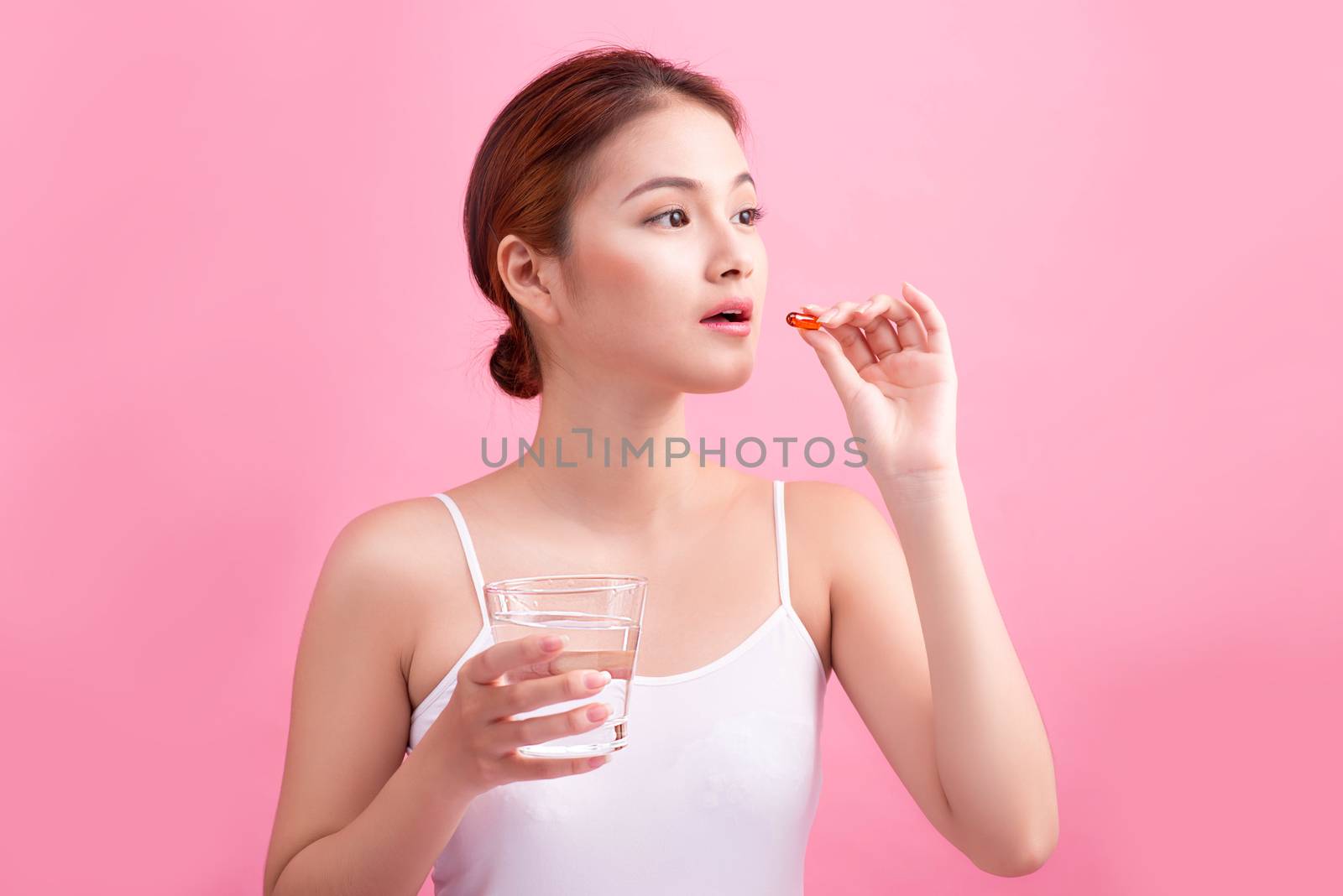 Young asian beauty young woman eating pills and drinking water o by makidotvn