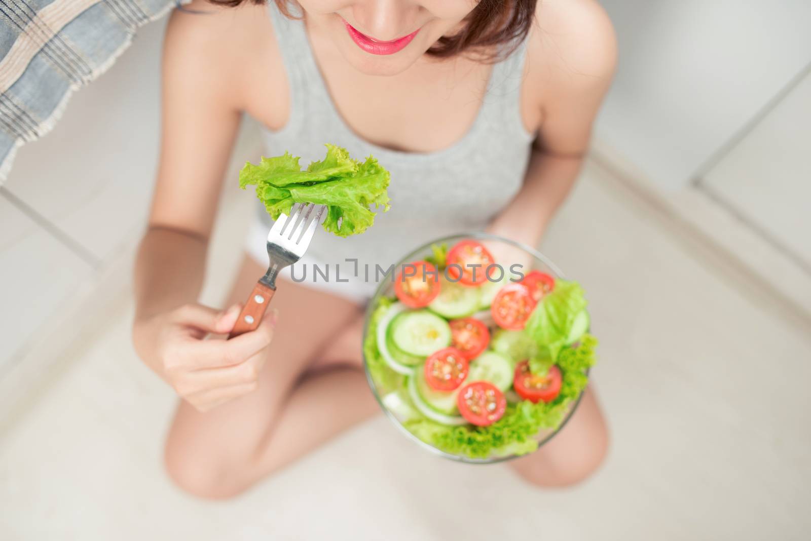 Beautiful young asian girl eating salad. smiling happy girl eating healthy food.