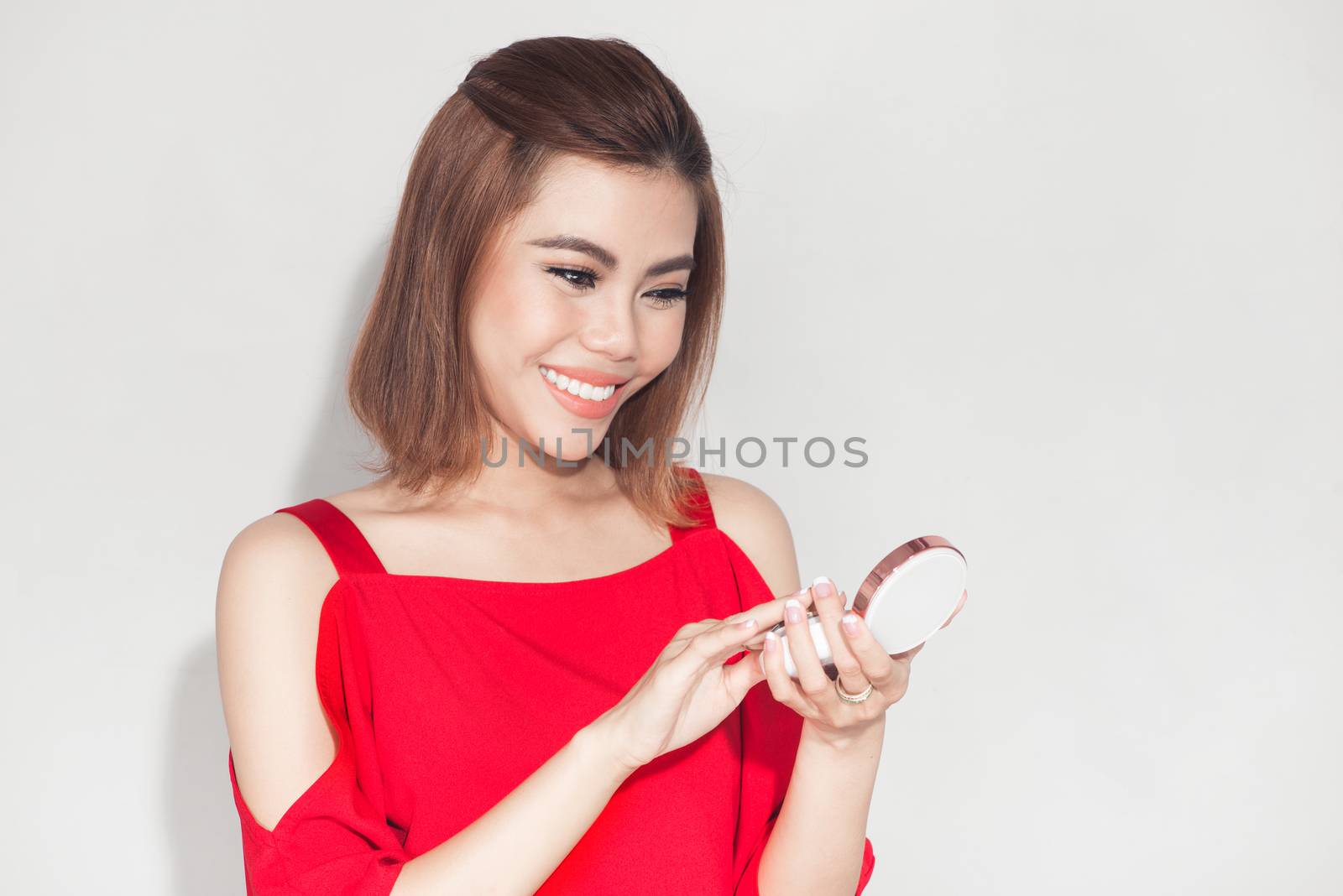 Fashion lifestyle portrait of young asian woman holding foundati by makidotvn
