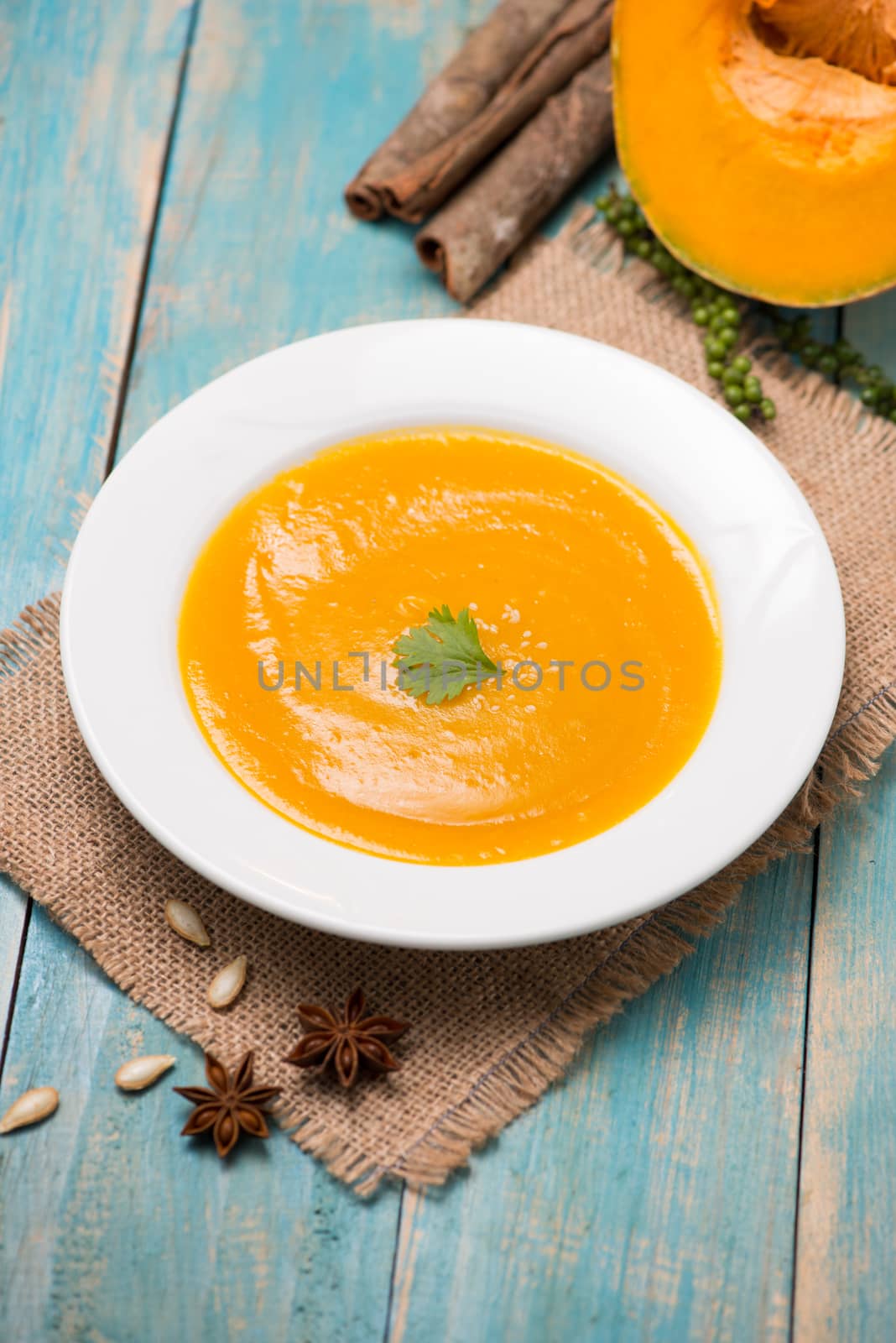  Top view of pumpkin and carrot soup with cream and parsley on blue  wooden background.