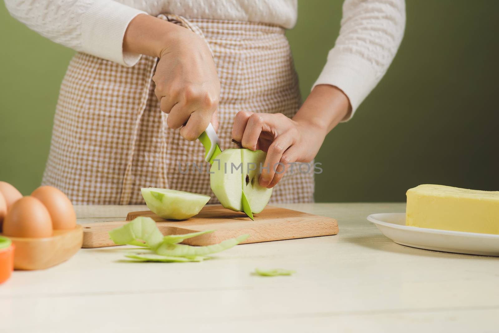 House wife wearing apron making. Steps of making cooking apple cake. Cutting green apple.