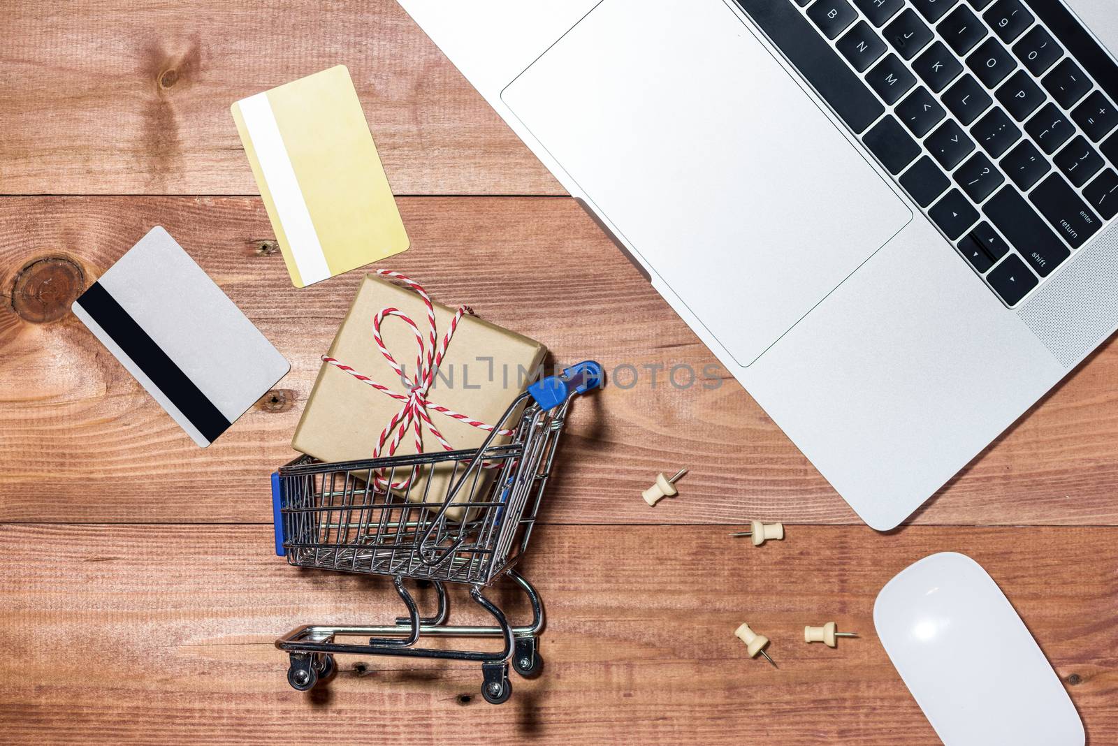 Shopping online concept. Small blue trolley and gadgets on the wooden table.