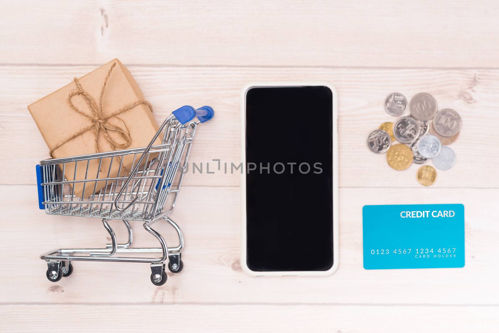 Shopping online concept. Small blue trolley and gadgets on the wooden table.