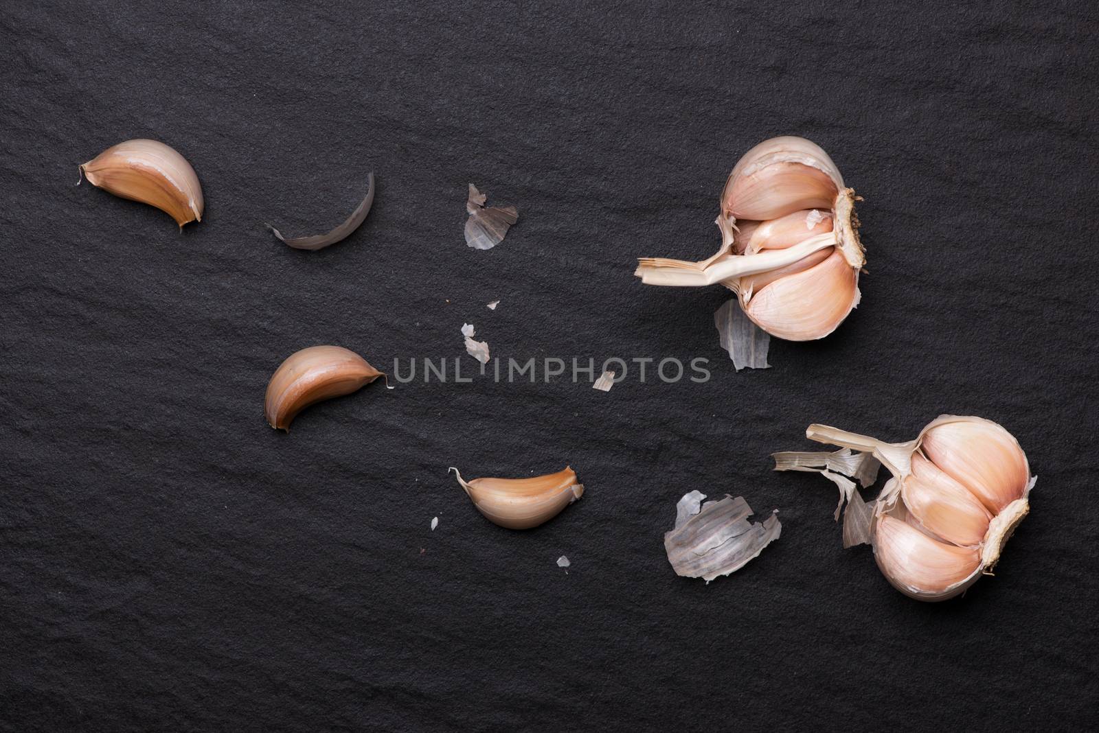 Garlic Cloves and Garlic Bulb on black stone table. by makidotvn