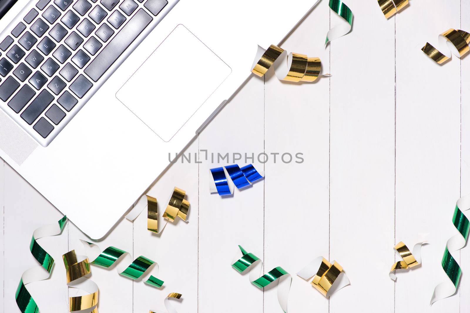 Celebration Flat lay with colorful party items and laptop on wooden background.