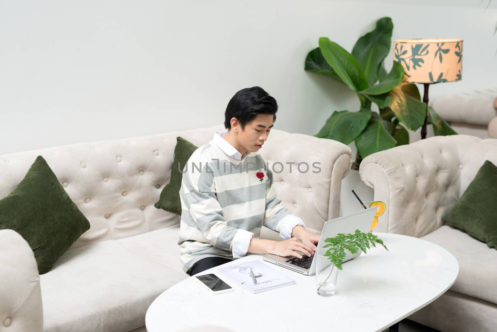 Asian young businessman working on his laptop in a coffee shop