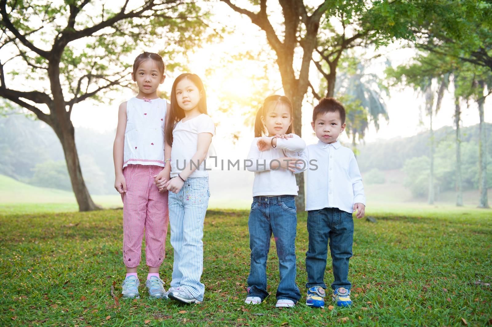 Portrait of Asian children at park. Kids having fun outdoors. Morning sun flare background.