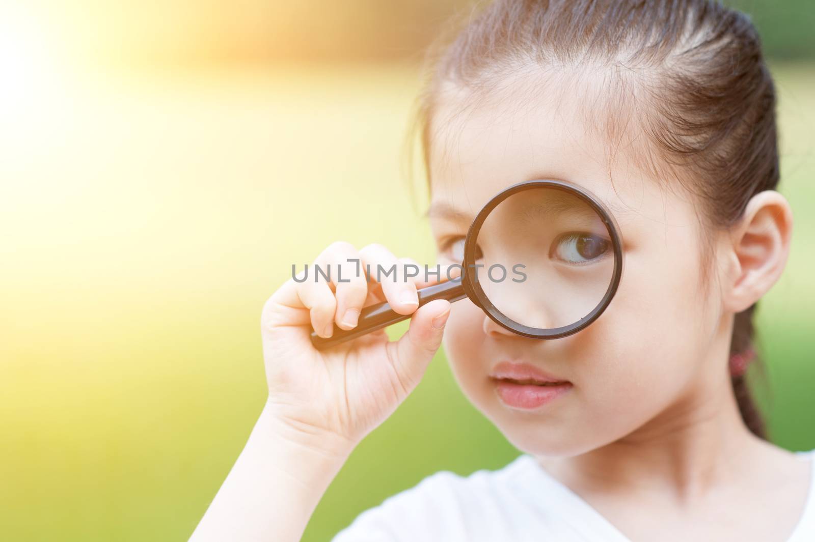 Asian child with magnifier glass at outdoors. by szefei