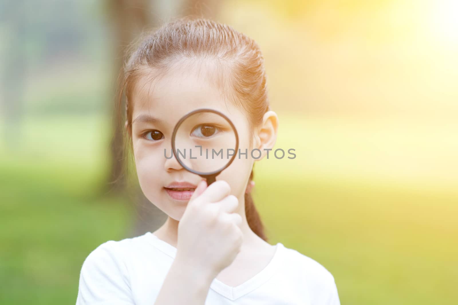 Little girl with magnifier glass at outdoors. by szefei