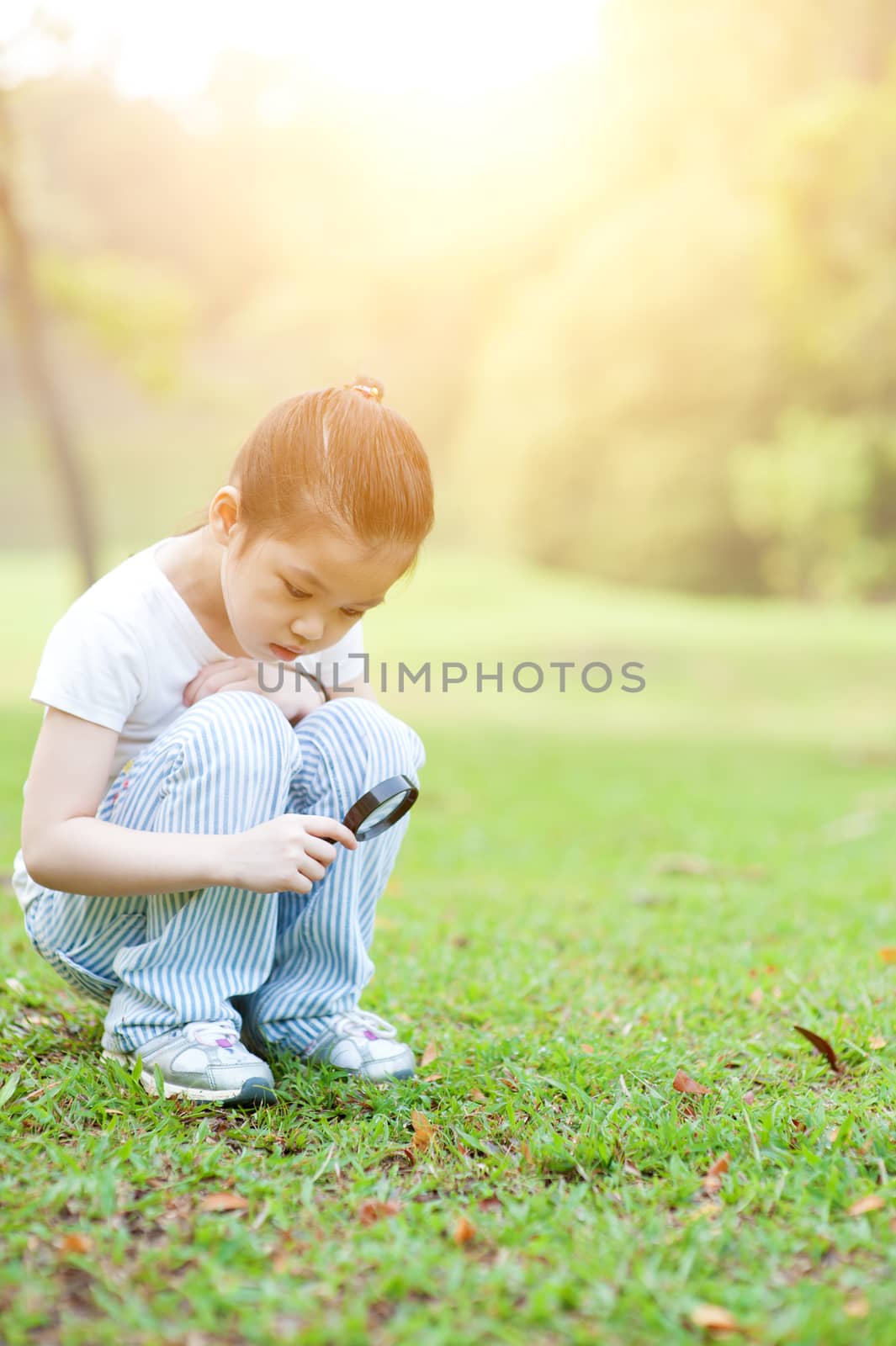 Kid exploring nature with magnifier glass at outdoors. by szefei