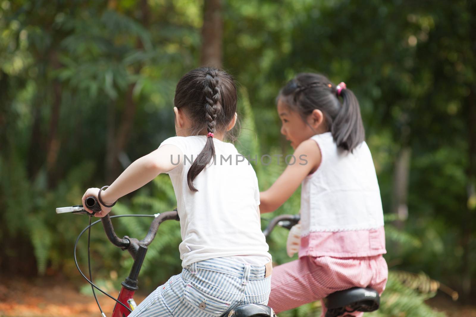 Active Asian children riding bike outdoor. by szefei