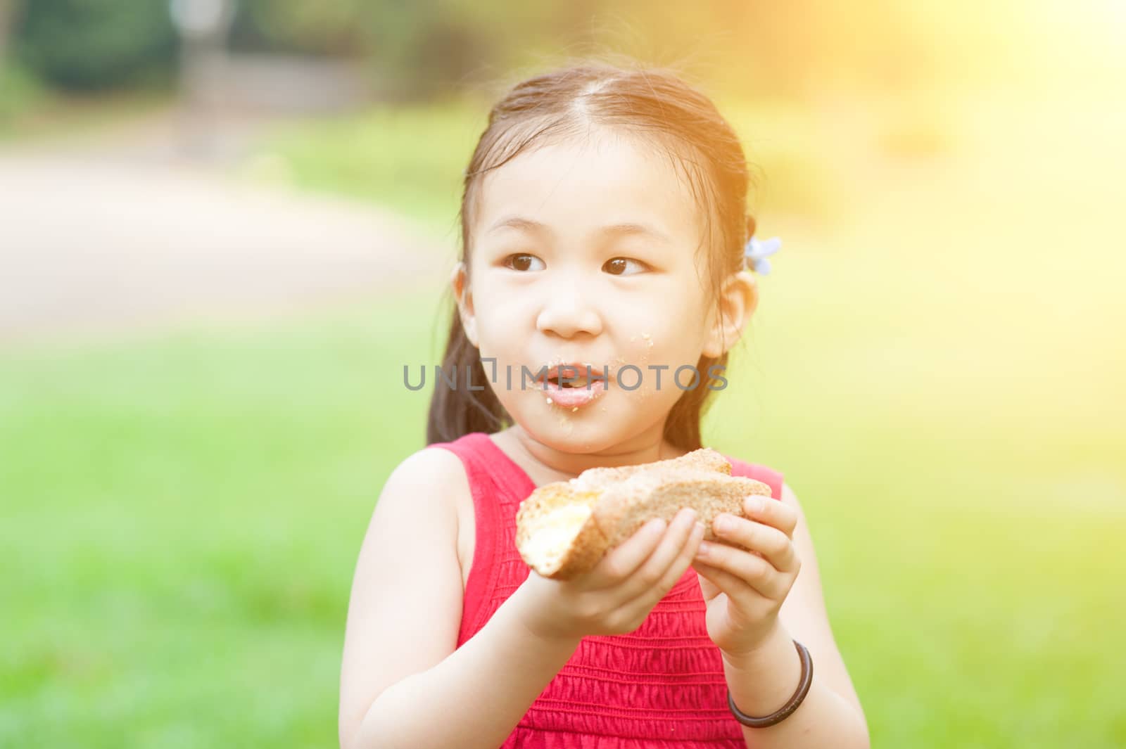Asian kid eating outdoors. by szefei