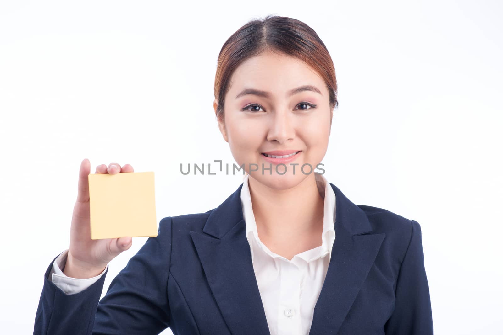 A portrait of a young smiling business woman showing blank sticky note isolated on white background.