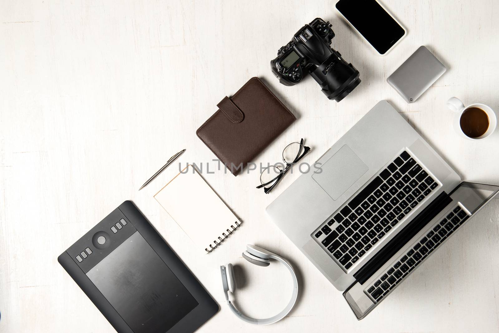 Work space for photographer, graphic designer. Flat lay of laptop, camera, colorchart, digital tablet, coffee cup, book, pencil on wooden table.