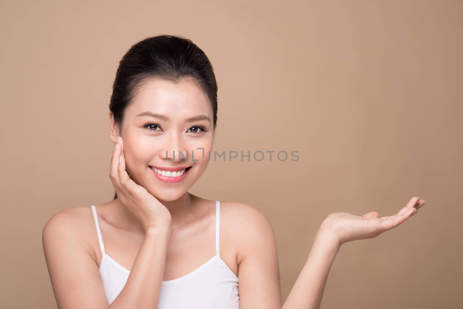 Proposing a product. Beautiful spa woman showing empty copy space on the open hand palm