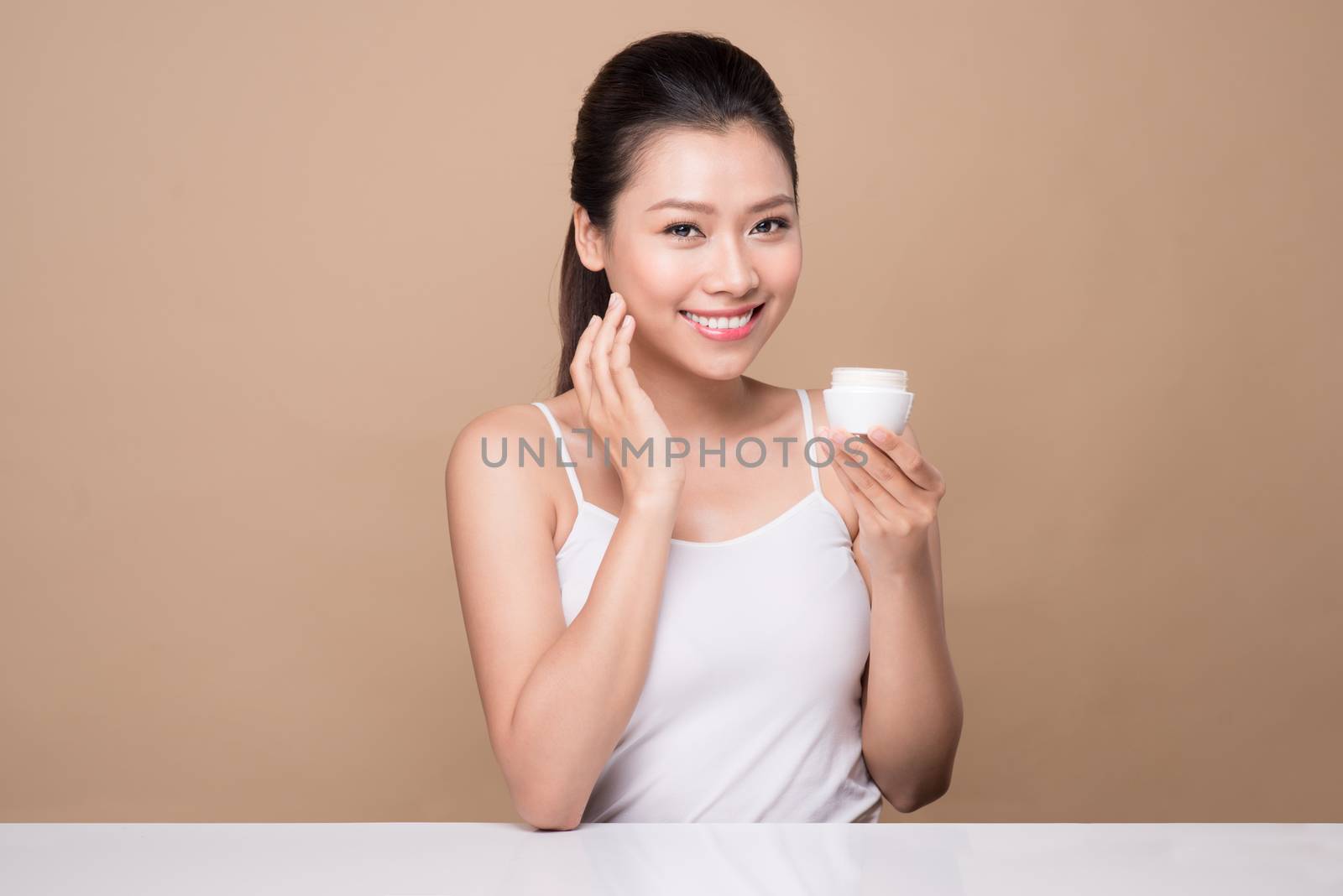 Skincare. Beautiful asian woman show moisturizer or lotion produ by makidotvn