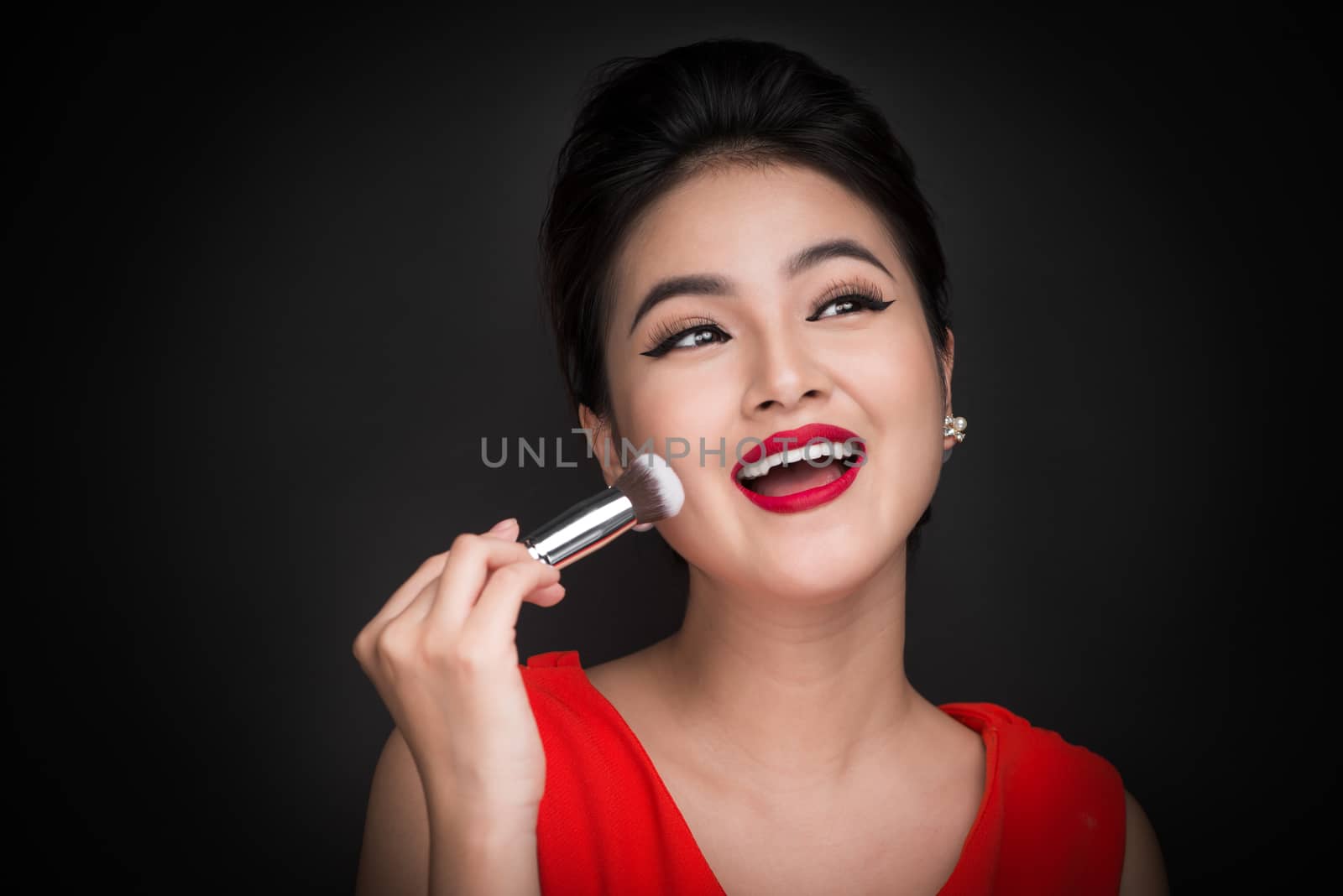 Cosmetic powder brush. Asian woman applying blusher on her cheeks with perfect make-up and red lips