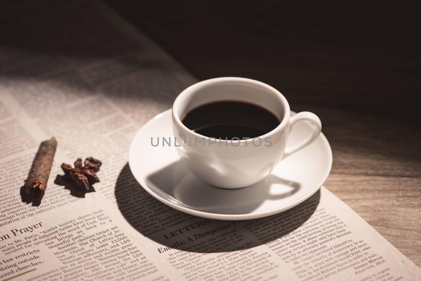 Male hands holding a cup of coffee over wooden table.