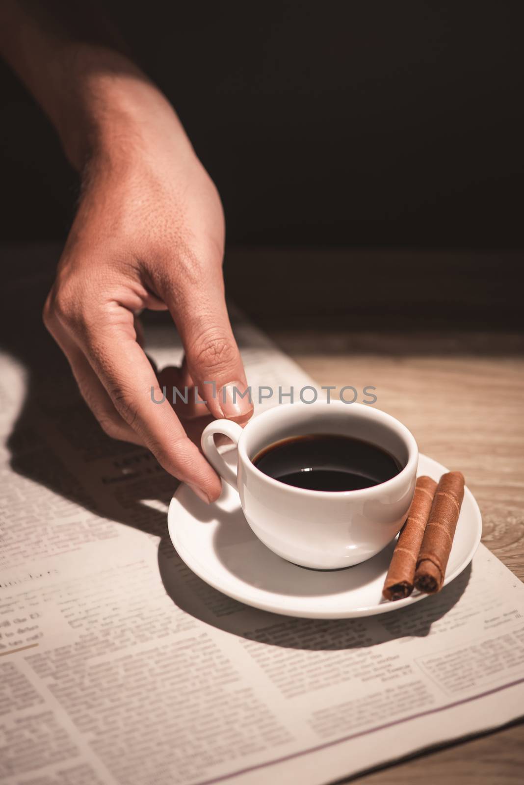 Male hands holding a cup of coffee over wooden table. by makidotvn