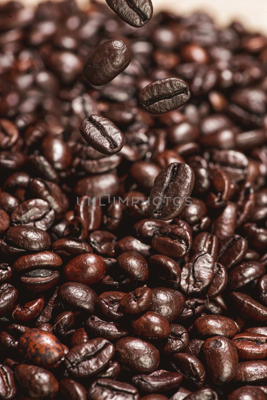 Dark coffee beans falling on the table by makidotvn