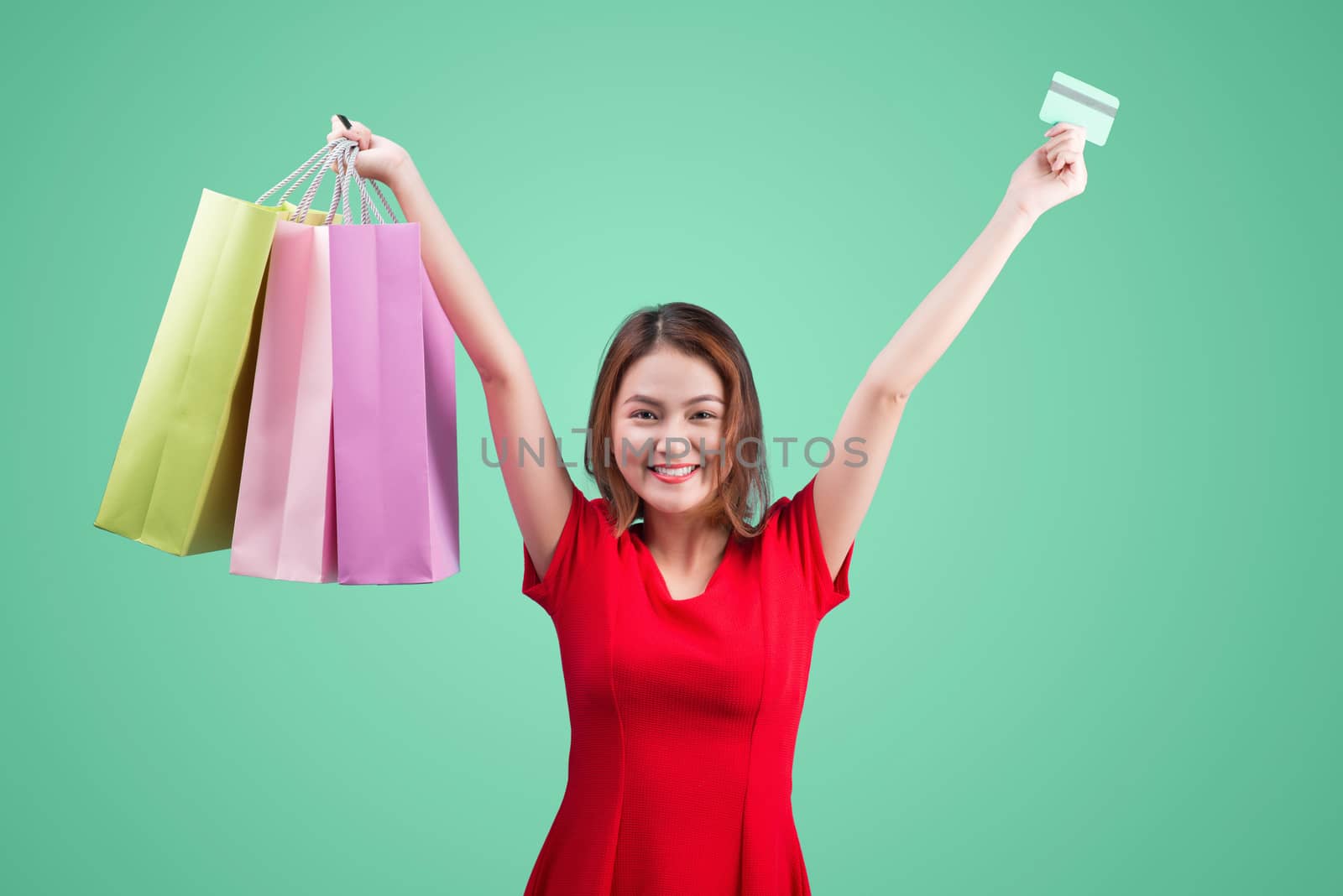 Santa asian woman holding shopping bags and credit card against blue vignette