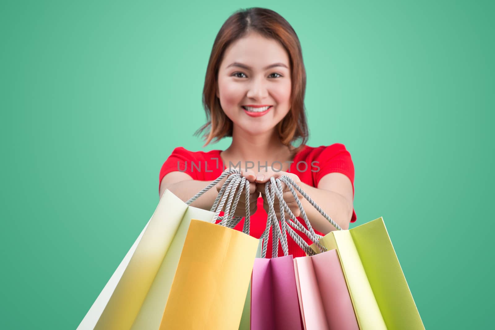 Beautiful young asian woman with colored shopping bags over blue by makidotvn