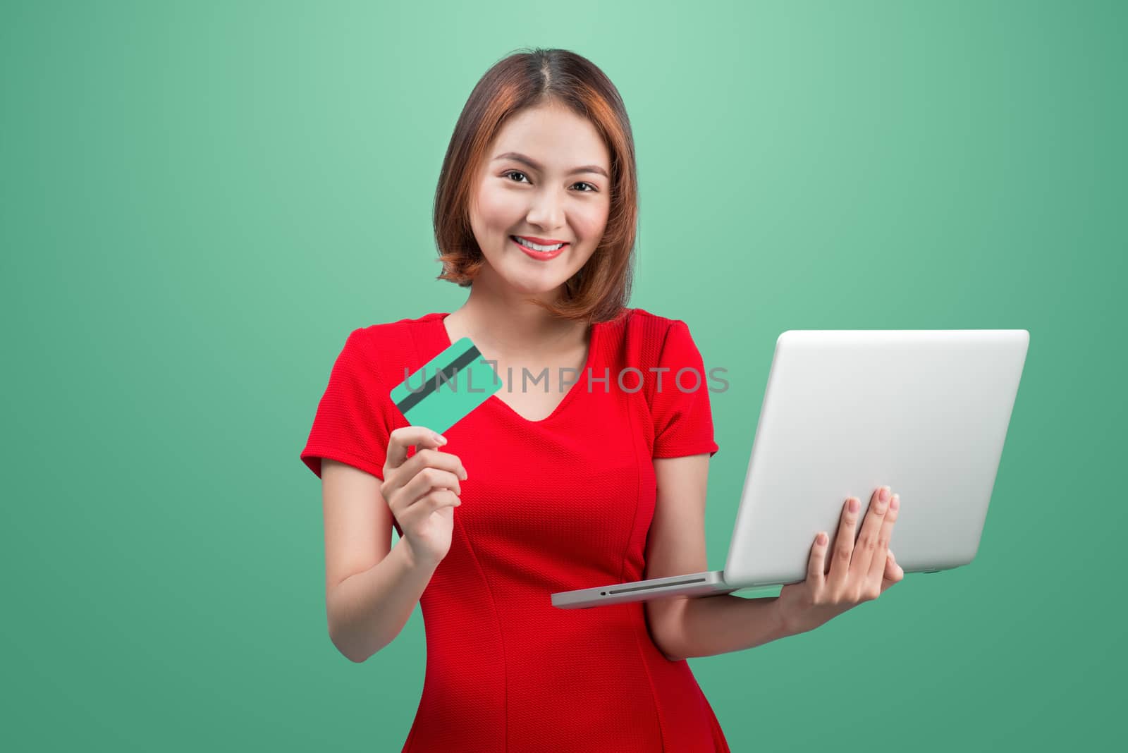 Online shopping. Asian woman holding laptop and credit card read by makidotvn