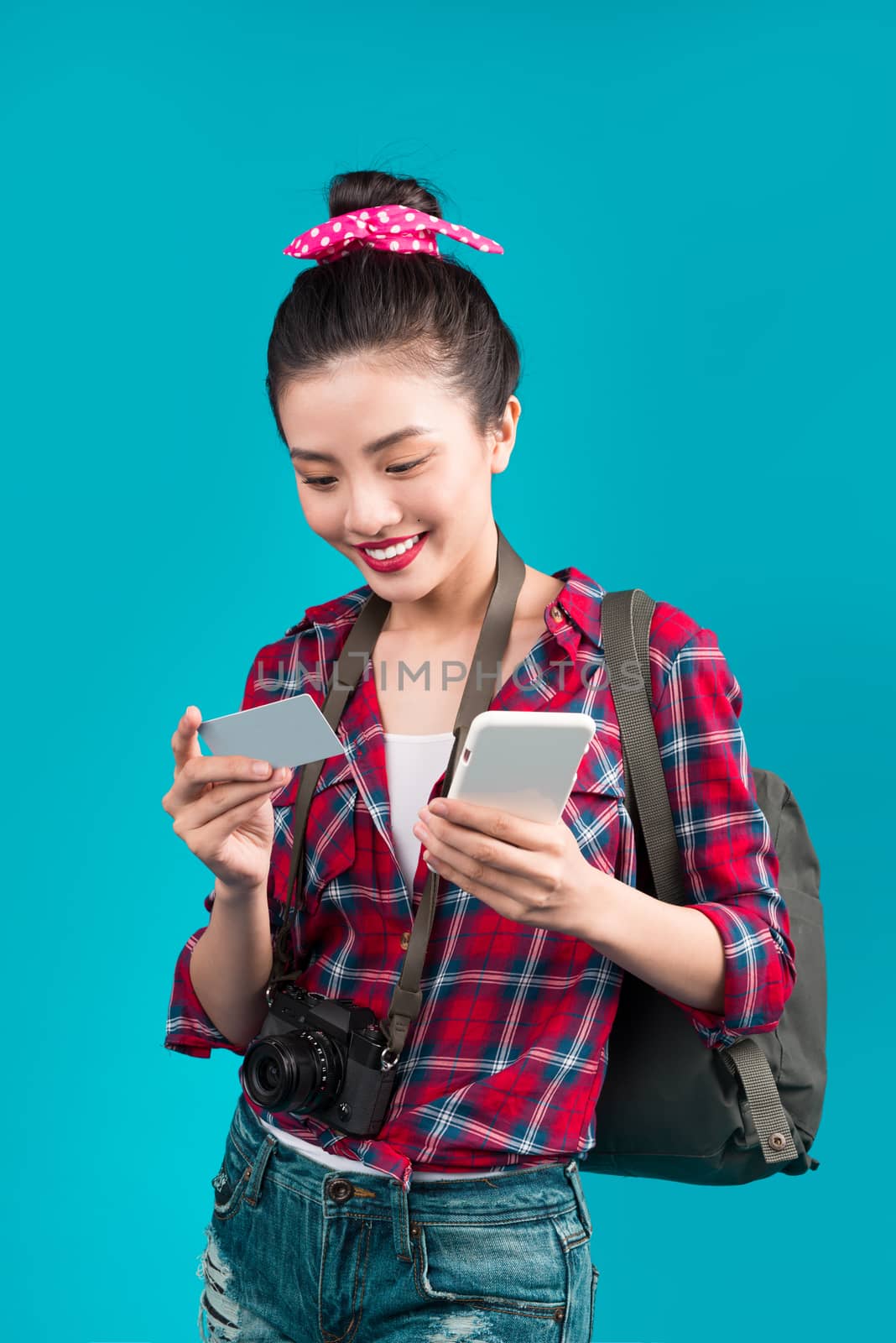 Happy young asian woman holding credit card and smartphone stand by makidotvn