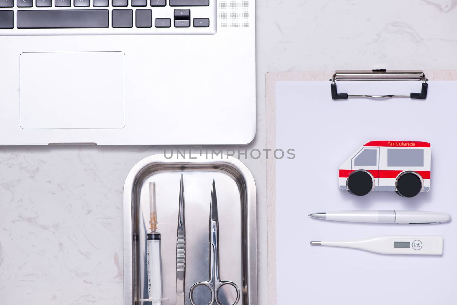 Workplace of a doctor. Laptop, clipboard and other stuff on desk.