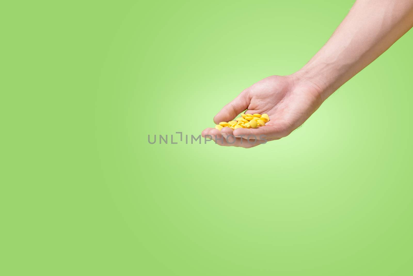 Yellow pills in hand on green background. by makidotvn