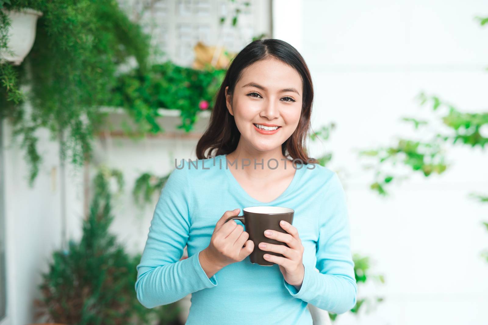 Portrait of a happy asian woman thinking and holding coffee or tea cup at breakfast 