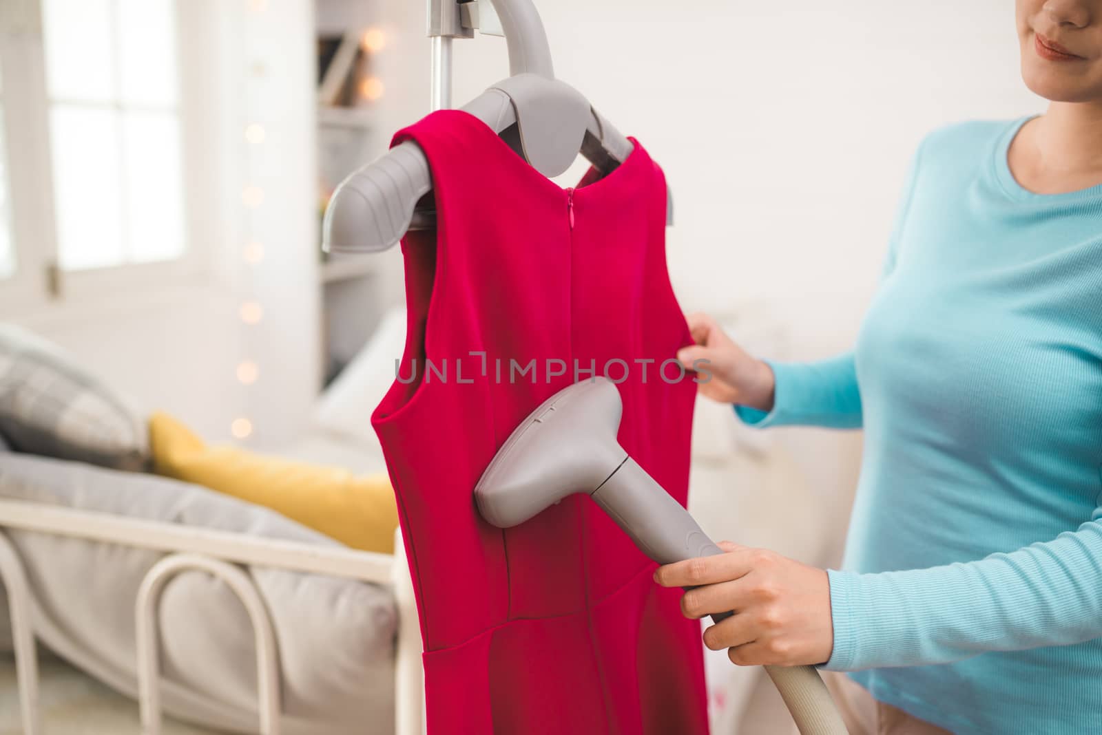 Happy young asian woman steaming clothes in room